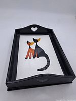 Full view of rectangular serving tray, black frame, white base with painted two cats design, heart cutouts on handles.