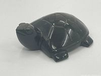 Smooth polished black obsidian turtle carved figurine shown from right side angle highlighting shell and head details.