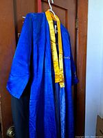 Blue silk robe hanging on door with yellow trim and visible 'Duke' embroidery