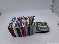 Photo showing all 20 Playstation game cases arranged on a white surface from a side angle.