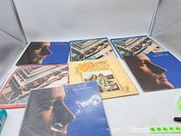 Photo showing five LPs with three Phil Collins albums and one John Denver album.