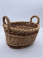Full view of small oval wicker basket with loop handles on each side showing overall condition and shape