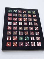 Full display board of fifty souvenir dice from Las Vegas hotels arranged in rows on black fabric.