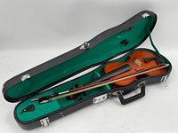 Full view of violin, bow, and open black hard case with green felt lining.