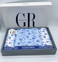 Three towel set in box: one bath towel and two face towels with blue floral print and Georges Rech logo band