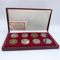Full view of six commemorative coins arranged in maroon velvet case with red exterior and white interior lid featuring Seoul 1988 Olympic logo and certificate card in top left corner.