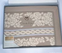 Blanket displayed in box showing floral pattern, braided detail, and Mila Schon embroidery.