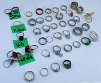 Wide view of all rings in assorted metals and designs with labeled marker notes.