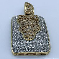 Front view of gold-plated pendant top covered with clear rhinestones and filigree center design.