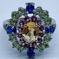 Front view of ring showing oval citrine center surrounded by alternating kyanite and peridot stones set in sterling silver.