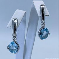 Pair of oval sky blue topaz sterling silver earrings shown from front view, highlighting the faceted gemstones and silver setting.