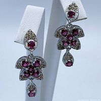 Front and angled view of the earrings highlighting the Rhodolite Garnet and Sapphire gemstone arrangement with sterling silver metal base.