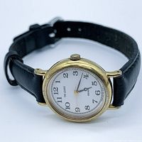 Front angled view of the Seiko The League gold-plated quartz ladies wristwatch with black leather strap, showing dial, case, and strap.