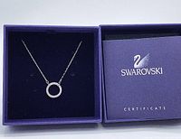 Swarovski Circle of Life pendant necklace displayed in its purple branded box alongside its certificate booklet.
