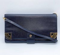 Front view of the navy blue leather clutch showing the gold-tone corner accents and shoulder strap.