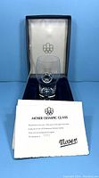 Clear Moser Olympic glass displayed inside original box lined with blue velvet and white satin. Certificate partially visible in front.