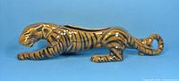 Side view of reclining ceramic tiger planter showing detailed striping and curled tail