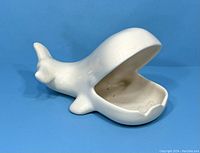 Side and front views of a whale-shaped ceramic ashtray showing overall shape, glaze finish, and interior condition