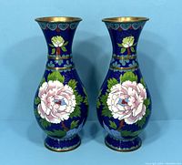 Front view of pair of vintage Chinese cloisonné vases with pink peony flowers and yellow birds on dark blue background.
