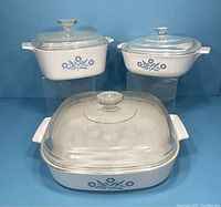 Three Blue Onion Corning Ware casseroles with glass lids: medium square, small round, large rectangular.