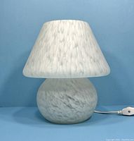 Front view of the vintage glass mushroom table lamp unlit, showing the lamp's rounded base and matching tapered shade with a swirled white glass pattern.