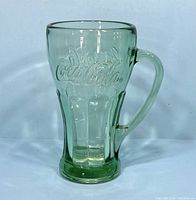 Side view of the green tint Coca Cola glass mug, showing the embossed logo and handle.
