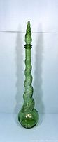 Full view of the tall green glass genie bottle decanter with decorative stopper, showing spiral textured pattern and bulbous base.