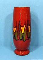 Front view of the red vase showing the abstract multicolor drip pattern and pedestal base.
