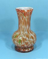 Front view of vintage Murano glass bud vase on blue background showing mottled orange, white, and green glass pattern