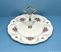 Two-tier serving tray showing front view with floral pattern and diamond-shaped metal handle.