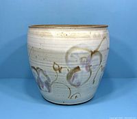 Front view of vintage pottery planter showing floral decoration on light background with a brown unglazed rim.