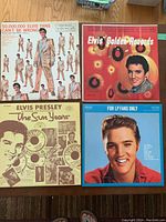 Four Elvis Presley LP records laid flat on a wooden surface, showing album covers.