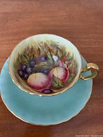 Top view of teacup on saucer showing interior hand‐painted fruit design