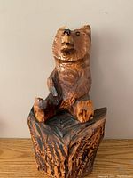 Front view of the hand-carved wooden bear sitting on a carved base showing detailed fur texture and nose painted black.