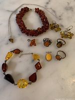 Overview photo showing the full assortment of amber and sterling silver jewelry including bracelets, rings, earrings, pendant, and brooch.