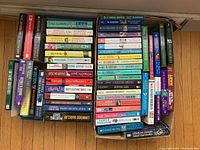Three photos showing stacks of paperback books from various mystery and fiction authors in like-new condition