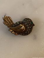 Front view of bird-shaped brooch showing silver metal and marcasite stone decoration.