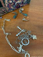 Photo showing assorted sterling silver jewelry, including bracelets, rings, and dangling earrings with turquoise stones, and pendants on chains.