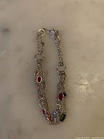 Full view of the multi-strand sterling silver bracelet with colorful stones on marble background.