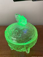 Lidded candy dish made of uranium glass glowing green.