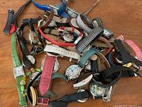 Photo showing a pile of various wristwatches with many different band colors and materials, including leather, fabric, and metal stretch bands.