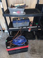 Black and red CleverMade toolbox on the floor, plastic bin with hammers and other hand tools on top black plastic shelves, blue Craftsman toolbox, and a metal level.
