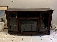 Front view of dark wood electric fireplace cabinet with glass doors and mirrored electric fireplace insert.