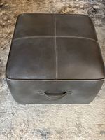 Top view of the dark brown leather ottoman showing stitched cross pattern and square shape.