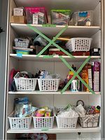 Full view of three shelves filled with plastic storage bins and baskets containing various household items including light bulbs, tools, baking supplies, and miscellaneous supplies.