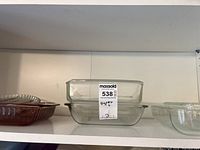 Two clear rectangular Pyrex glass baking dishes stacked, labeled with lot tag.