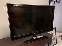 Samsung flat panel TV displayed on stand with remote resting on the base.