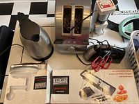 Overview of all kitchen appliances and gadgets including toaster, kettle, hand mixer, mandolin, chopper, and sprayer, showing condition and packaging.
