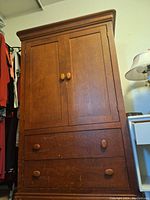 Front view of wooden dresser showing two door panels and three pull-out drawers with wooden knobs.