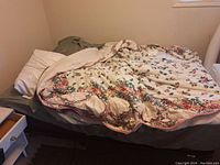 Photo of queen size bed with floral patterned comforter and pillows on it, showing overall condition and bedding present.